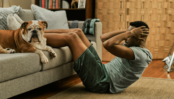 Man doing crunches in living room with dog