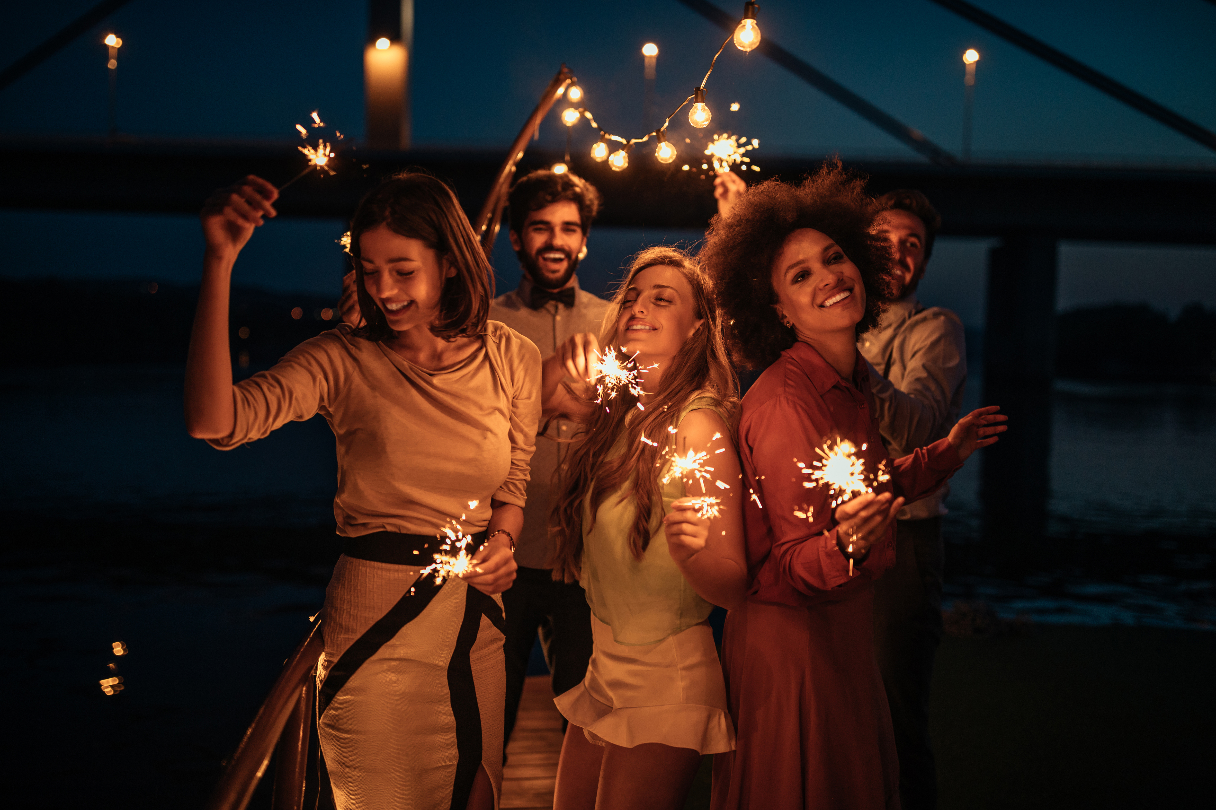 Group of people celebrating with sparklers in backyard