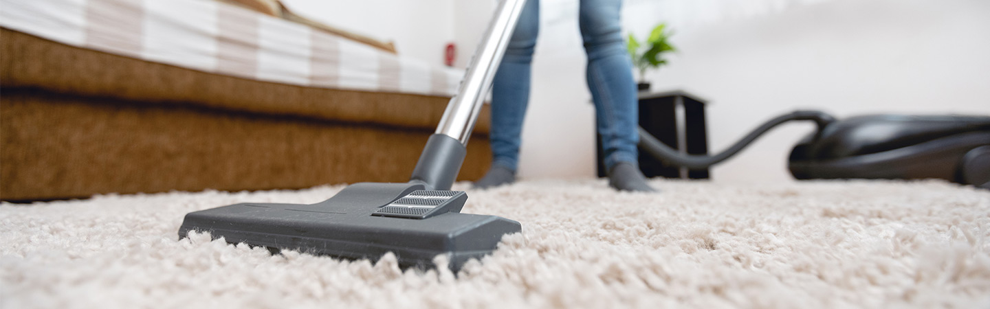Someone vacuuming the carpet to help get rid of debris, dust and other potential irritants.