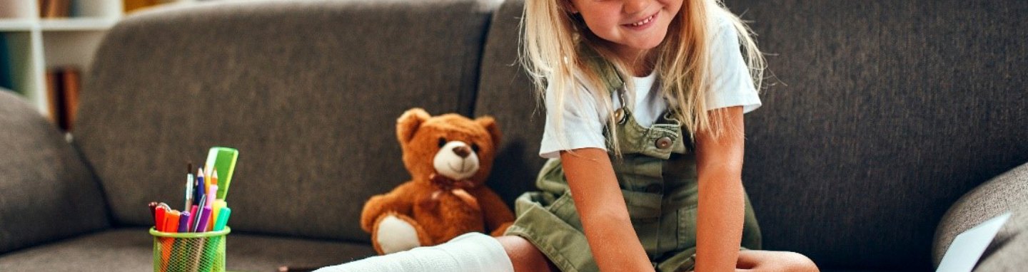Girl with broken leg coloring on couch.