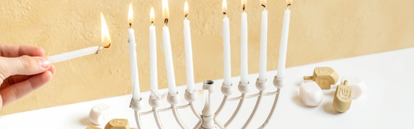 Person lighting a menorah for a holiday celebration.