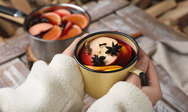 close-up of hands holding a cup of holiday wassail