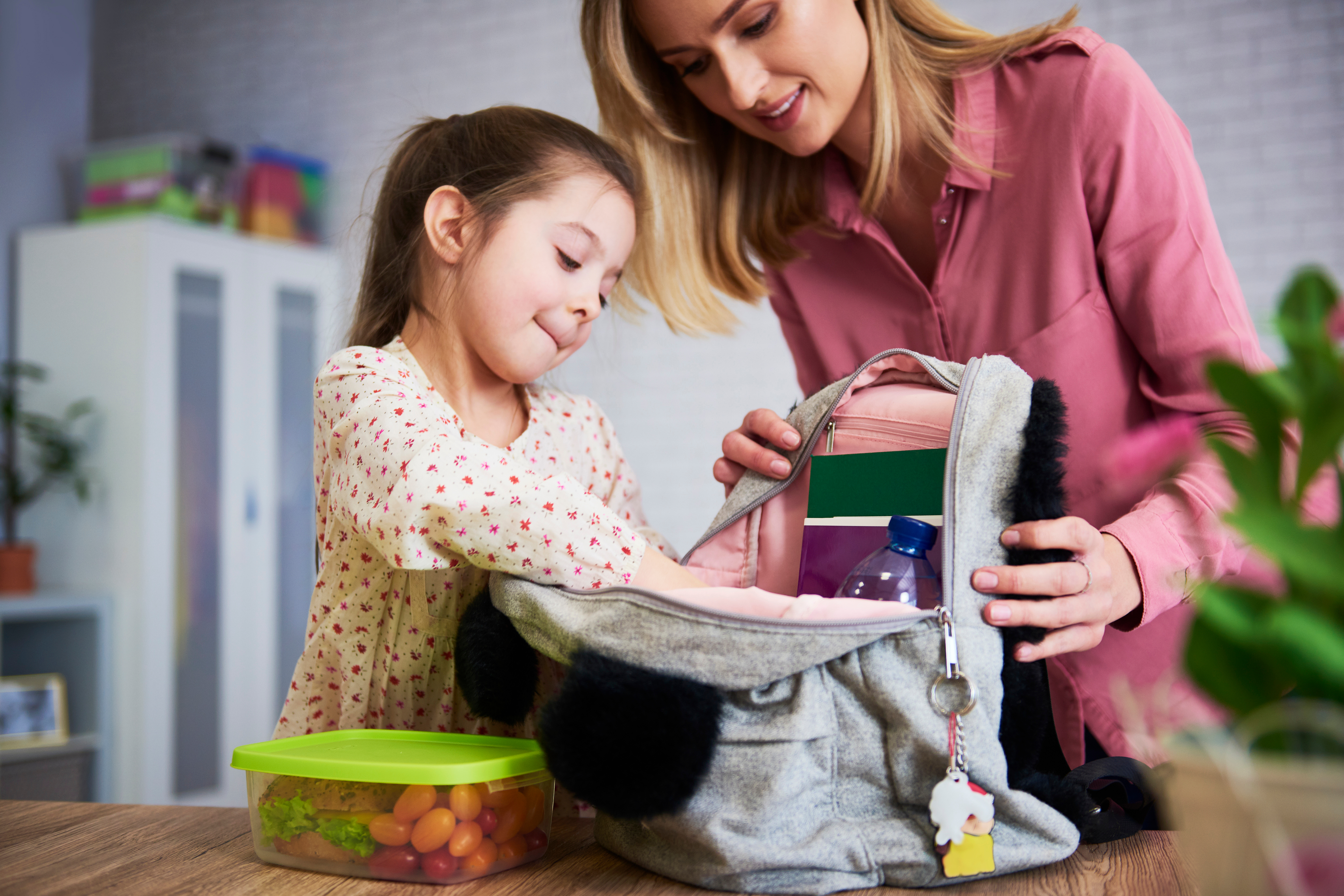 Mom and daughter packing backpack for school