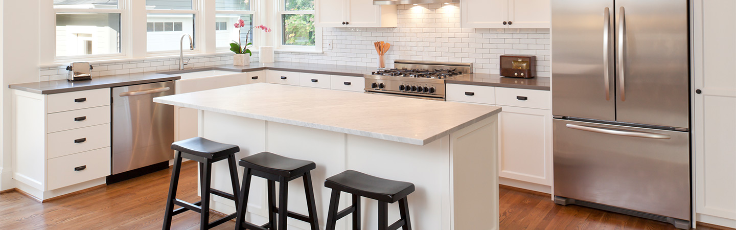 Clean kitchen with island and barstools.